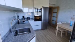 a kitchen with a sink and a table in it at Piso Escaravello - Laxe in Laxe