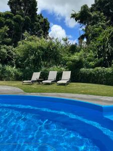 two lounge chairs sitting next to a swimming pool at Ocean views, indoor and outdoor brilliance! in Haleiwa