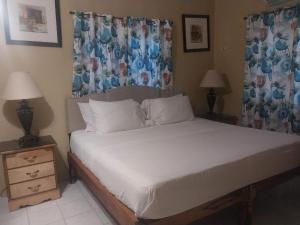 a bedroom with a bed with white sheets and two lamps at Brytan Villa in Treasure Beach