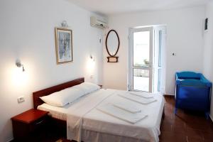 a bedroom with a bed with white sheets and a blue chair at Apartments Baron in Sveti Stefan