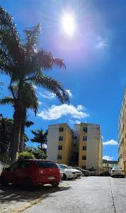 a red car parked in a parking lot with a palm tree at AP 3 quartos -2min da ARENA MRV e Expominas- BH in Belo Horizonte