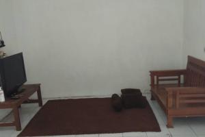a living room with a tv and a brown rug at homestay Icut syariah in Sambong-hilir