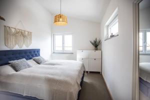 a bedroom with a bed with a blue headboard and windows at Ferienwohnung Schottenhof Walser 4 - Alleinlage im Grünen mit Panoramablick in Achberg