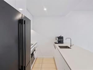 Una cocina con encimeras blancas y un refrigerador negro. en 2BR Apartment in South Brisbane with Spectacular River View, en Brisbane