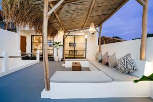 een buitenwoonkamer met een bank en een rieten dak bij Villa Valentina - 2 bedroom private luxury villa in Canggu quiet area in Canggu