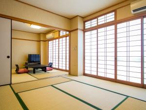 - un salon avec de grandes fenêtres et un piano dans l'établissement Kannawa Yunoka, à Beppu