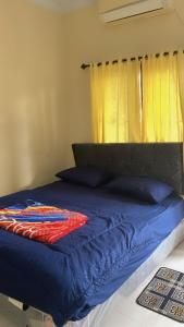 a bed with a blue comforter and some pillows at Din's House in Legian