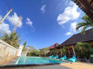a swimming pool with blue pillows next to a house at Jepun Bali Bungalow in Nusa Lembongan
