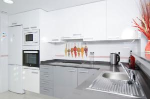 a white kitchen with a sink and a refrigerator at Novabeach by Mar Holidays in Puerto Marino