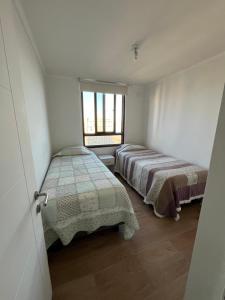 two beds in a small room with a window at Departamento JARDIN DEL MAR, 2 Dormitorios in Coquimbo