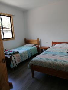 a bedroom with two beds and a window at Mini departamento 2 in Coñaripe