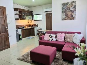 a living room with a purple couch and a kitchen at Arabella's Home in Dumaguete