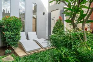 a pair of white chairs sitting on a porch with plants at Modern 3BDR Villa - Between Seminyak & Canggu in Kerobokan