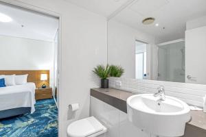 a white bathroom with a sink and a bed at Panoramic Views at Harbour Light on the Waterfront in Cairns