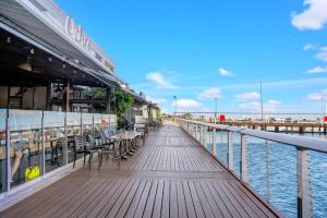 a boardwalk with tables and chairs next to the water at Panoramic Views at Harbour Light on the Waterfront in Cairns