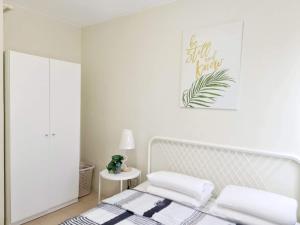 杜马格特Warm Time Cabin 2BR Condo Unit的白色的卧室配有一张床,墙上挂着一幅画