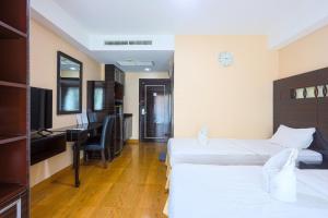 Una habitación de hotel con dos camas y un escritorio. en Land Royal Residence Pattaya, en Pattaya South