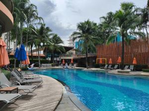 a pool at a resort with chairs and umbrellas at 7 Floor - Studio Room at TBHR near Kata beach in Kata Beach