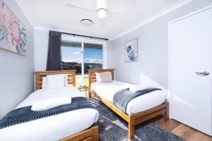 two beds in a room with a window at Magpie Rest in Forster