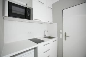 Eine weiße Küche mit Mikrowelle und Spüle in der Unterkunft Hotel Am Römerwall in Mainz