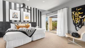 ein Schlafzimmer mit einem weißen Bett und einem Stuhl in der Unterkunft The Lake House - The Vintage in Pokolbin