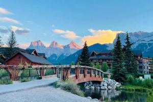 un pont sur une rivière avec des montagnes en arrière-plan dans l'établissement #304 Mountain View 1BR in Canmore DT, à Canmore