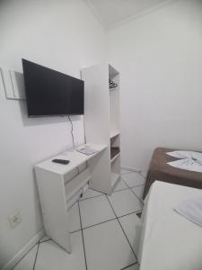 a white room with a desk and a tv on a wall at Hotel Aconchegante in Jequié