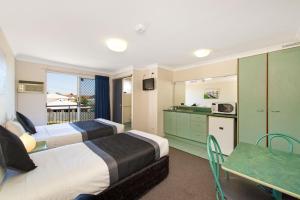 a hotel room with two beds and a table and a kitchen at Chermside Court Motel in Brisbane