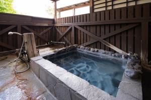 a jacuzzi tub in a building with a fence at Hozanso Beppu in Beppu