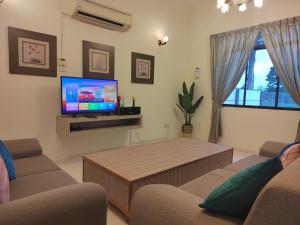 a living room with a couch and a tv at Luxpro Karaoke Private Pool Villa 218 in Kampong Pulau Sebang