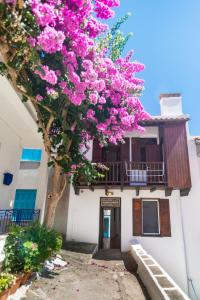 a tree with pink flowers in front of a building at The Bougainvillea in Skopelos Town