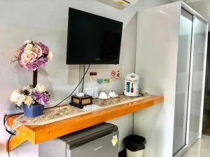 a shelf with a television on a wall with flowers at Mg Thung Song Hotel in Thung Song