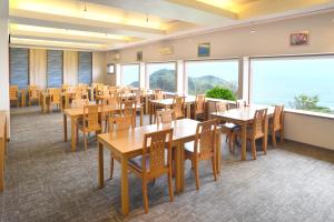 a restaurant with tables and chairs and large windows at SADO二ツ亀ビューホテル in Sado