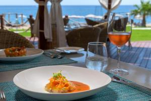ein Tisch mit einem Teller Essen und einem Glas Wein in der Unterkunft Rodos Palladium Leisure & Wellness in Faliraki