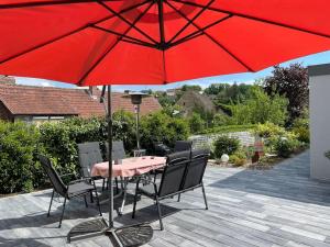 a red table and chairs under a red umbrella at Ferienhaus Mathilda in Kusel