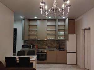a kitchen with a white refrigerator and a chandelier at Aušros Alėjos Apartamentai in Šiauliai