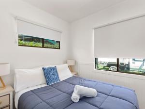 a bedroom with a blue bed and two windows at Shoalhaven Heads Village in Shoalhaven Heads