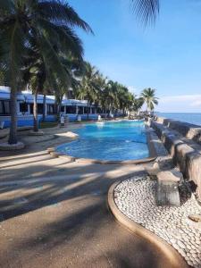 a swimming pool next to the ocean with palm trees at Navaphirom Resort Cha am in Cha Am