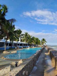 a swimming pool next to the ocean with palm trees at Navaphirom Resort Cha am in Cha Am