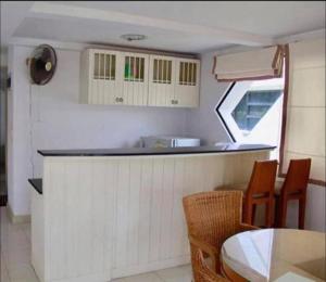 a kitchen with a counter and chairs and a table at Navaphirom Resort Cha am in Cha Am