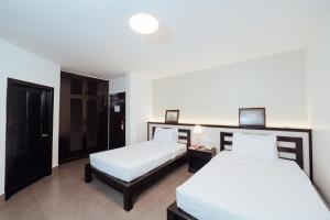 two beds in a hotel room with white sheets at Cambodian Country Club in Phnom Penh