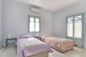 Un dormitorio con dos camas y dos ventanas. en Sunset Villa in Paros, en Santa Maria