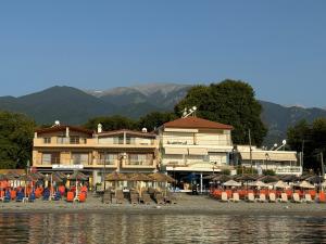 a hotel with chairs and umbrellas next to the water at APARTMENTS by the SEA in Leptokarya