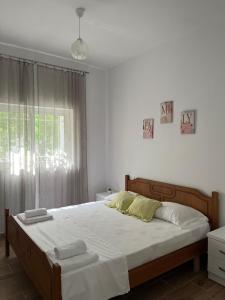 a bedroom with a bed with white sheets and a window at Doris Apartments in Himare