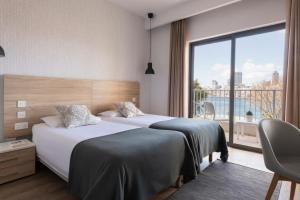 a hotel room with two beds and a large window at Plaza Regency Hotels in Sliema