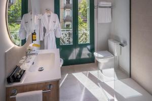 Un baño blanco con lavabo y espejo. en SERHS Carlit Boutique Hotel, en Barcelona