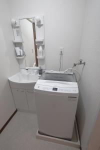 ein weißes Badezimmer mit Waschbecken und Spiegel in der Unterkunft LN20 NEW KOBE VILLA JR神戸駅徒歩7分!ペット可!最大16名宿泊可能な一軒家a in Kōbe + 41 Fotos