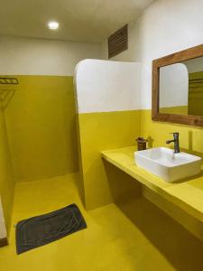 a yellow bathroom with a sink and a mirror at AVO Boutique Hotel in Dikoni