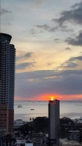 a sunset over a city with buildings and the ocean at COMFY 1-BR Condo near SLEC, US Embassy, Malls,Park in Manila +5 photos