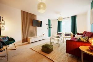 a living room with a red couch and a tv at Superb 4BR New House in Leeds